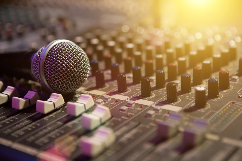 Studio d'enregistrement professionnel avec microphone dynamique à grille métallique posé sur console de mixage
