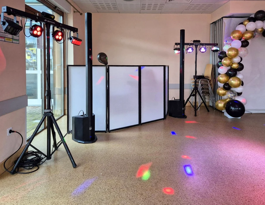 Scène de concert vide avec éclairage professionnel bleu, projecteurs à tête mobile positionnés sur la scène, faisceaux lumineux croisés créant une atmosphère spectaculaire dans une salle de spectacle